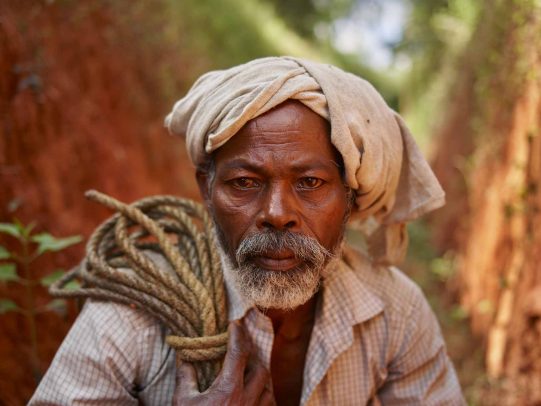 indian man with a white turban holding a rope on his shoulder