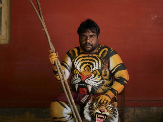 man painted with color of a tiger and tiger's face on his belly