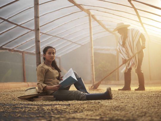 Girl studying in a coffee greenhouse while a man work in the background for Lavazza Calendar 2016 by Joey L