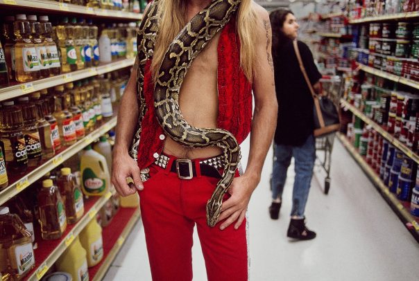 man with a snake around his neck in a supermarket