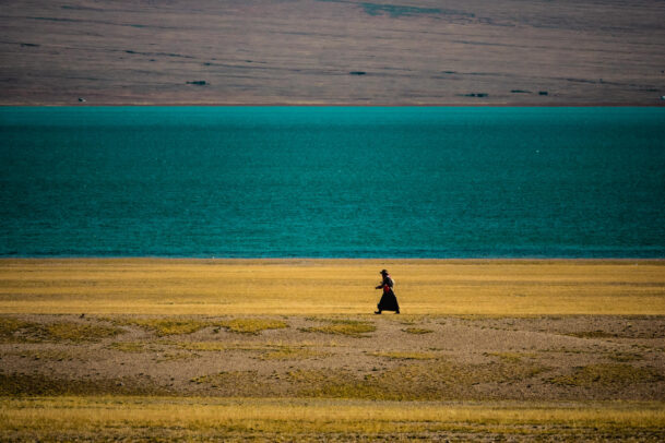 woman walking along a lake in Tibet