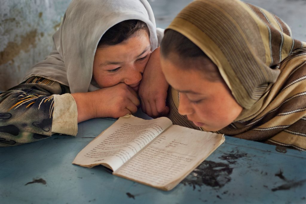 Two young girls read at school