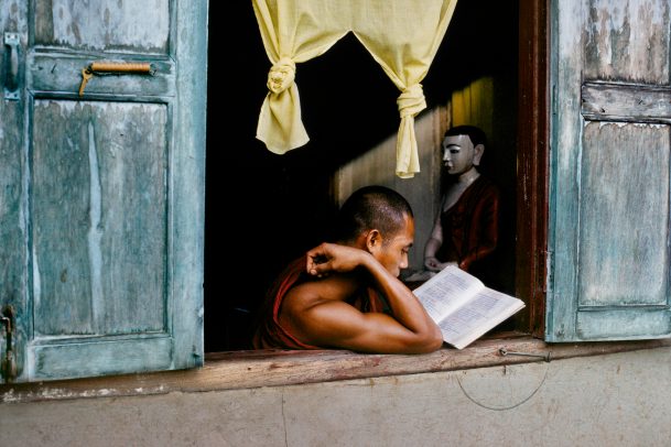 Monk reads scripture at window