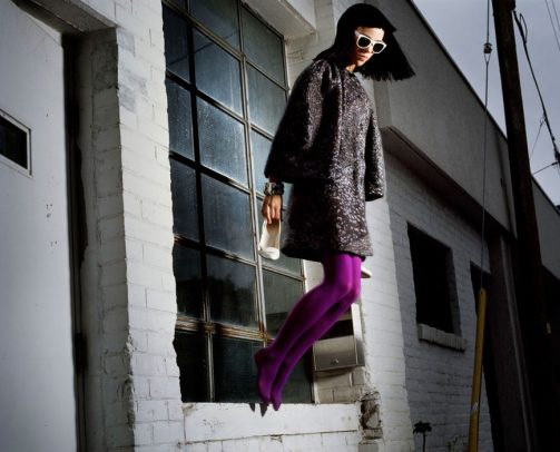 woman with coat and purple thights jumping out of the window