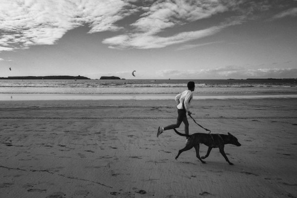 Person running on the beach with dog