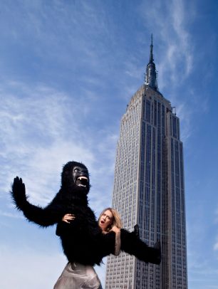 blond girl holding a person with a costume of monkey with Empire State Building in background