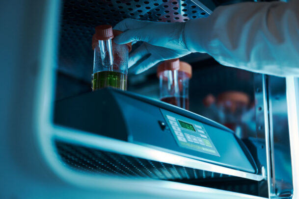 a hand with blue gloves testing liquids in laboratory during Novartis annual report by Joey L.