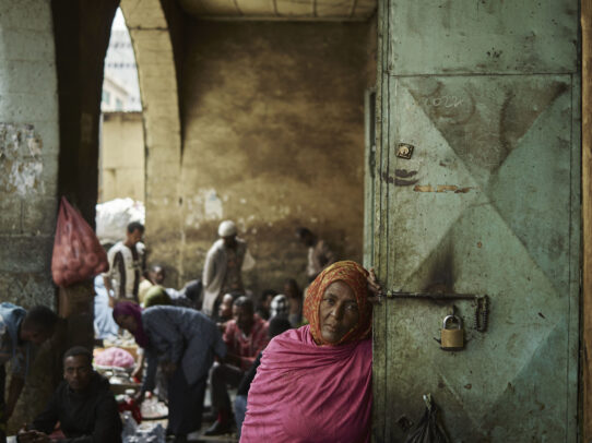 a woman leaning on a door in a market during Novartis annual report by Joey L.