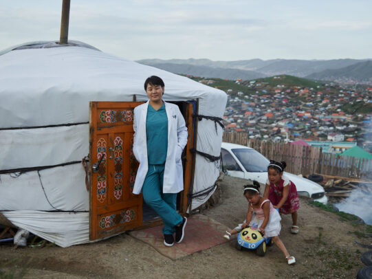 a doctor leaning on the entrance of a yurta during Novartis annual report by Joey L.