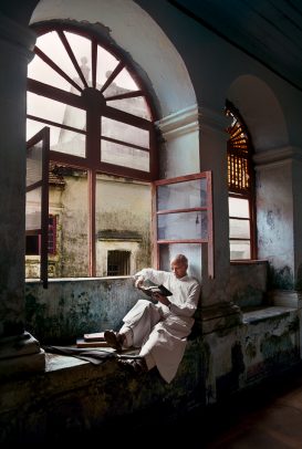 A man sits and reads by a window