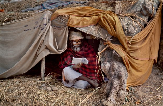 Man sitting in make-shift tent reading