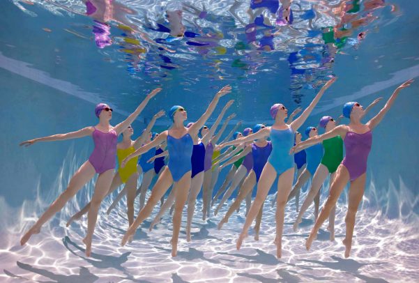girls dancing with colorful swimsuits and caps underwater