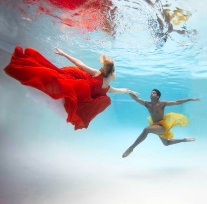 a couple dancing underwater with colorful dress