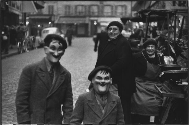 two children with a mask and a woman watching them