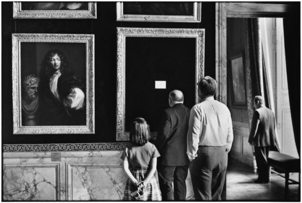 three people watching an empty frame in Versailles