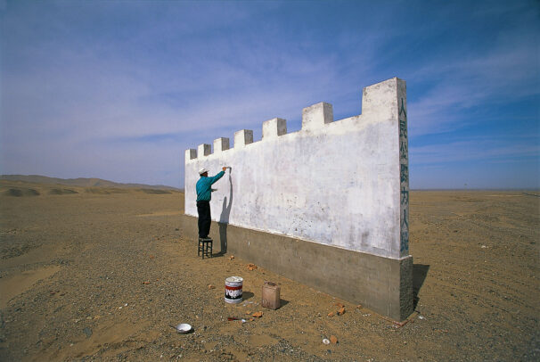 a man starts work on a Great Wall billboard in the desert near Dunhuang