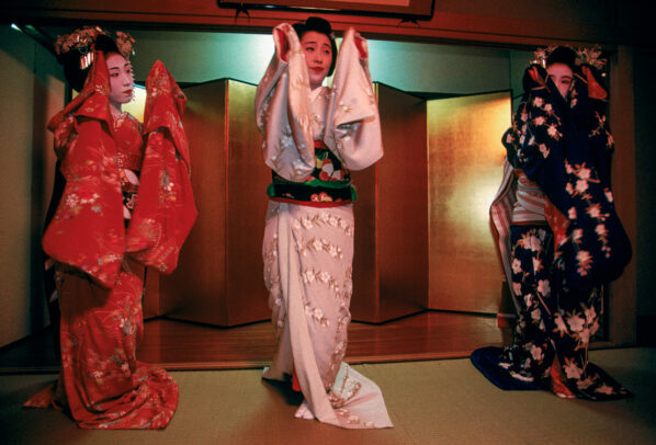 Three geisha in exquisite kimono dance at a party