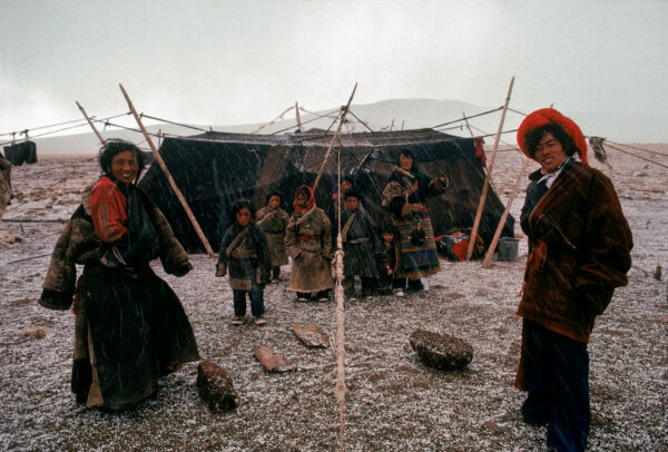 A Tibetan family in front of their yak-skin tent house while raining