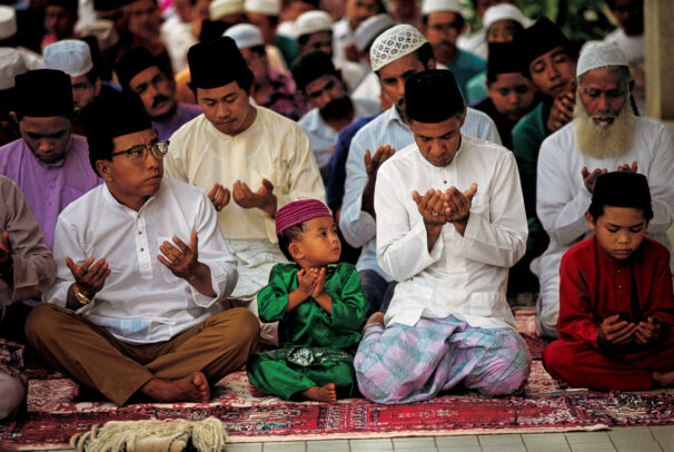 men and a child praying in a mosque