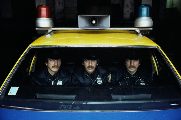 three policemen in a yellow car of police