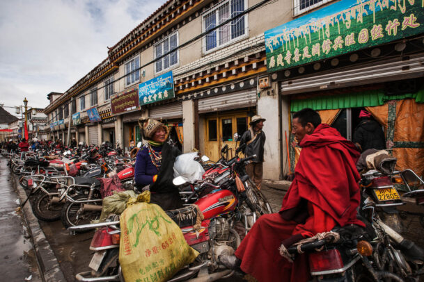 monks and a woman chatting near a long row of motorcycles