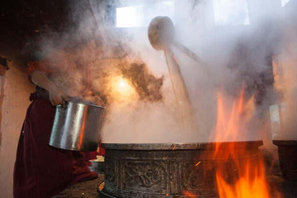 monk preparing yak butter tea with a big cauldron