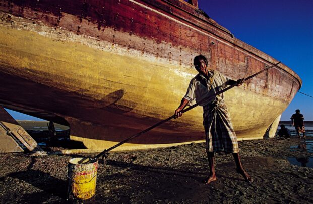 Sailors clean the hull of a dhow in Sur.