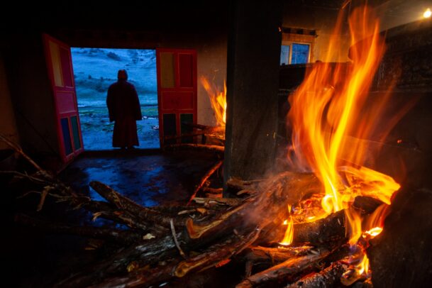burning fire and a tibetan monk in the background